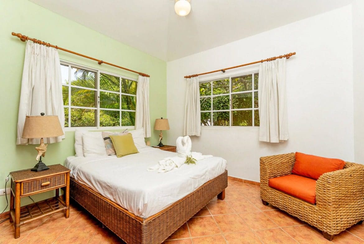 buyDRproperty Bedroom with a bed, wicker chair, and views of greenery in a villa. Sosua Real Estate
