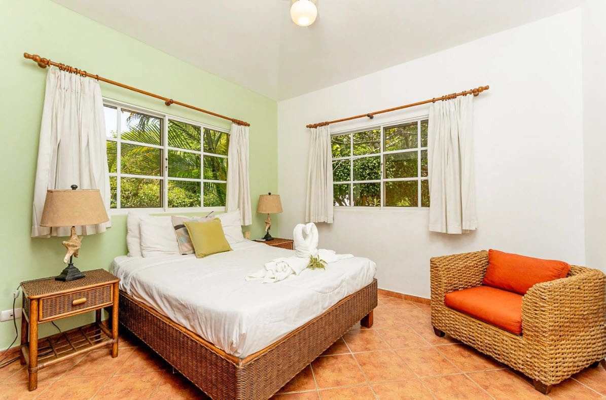 buyDRproperty Bedroom with a bed, wicker chair, and views of greenery in a villa. Sosua Real Estate