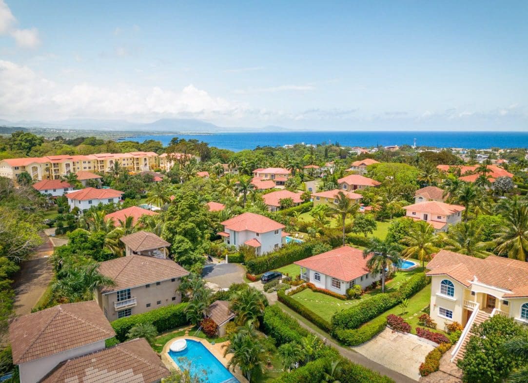 buyDRproperty Aerial view of a beautiful villa/home in a gated community with red tile roofs and ocean views. Sosua Real Estate