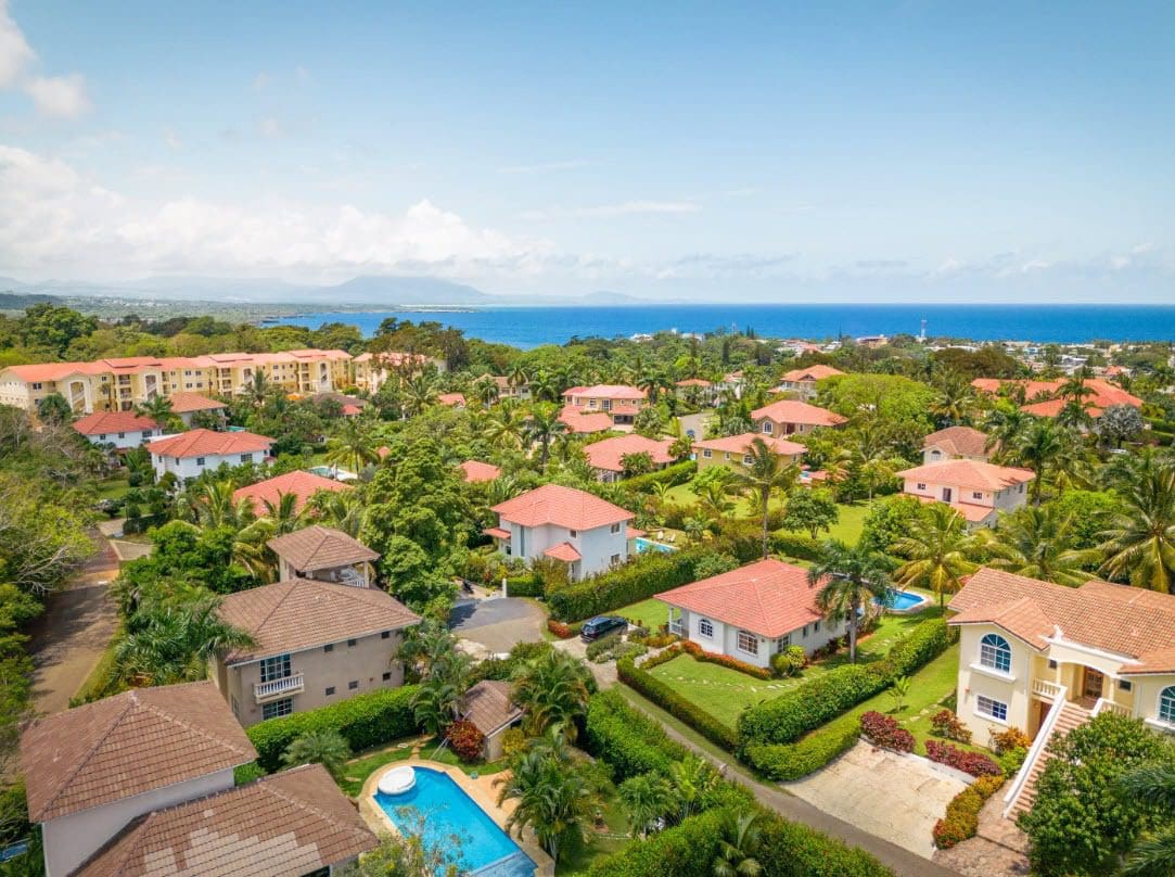 buyDRproperty Aerial view of a beautiful villa/home in a gated community with red tile roofs and ocean views. Sosua Real Estate