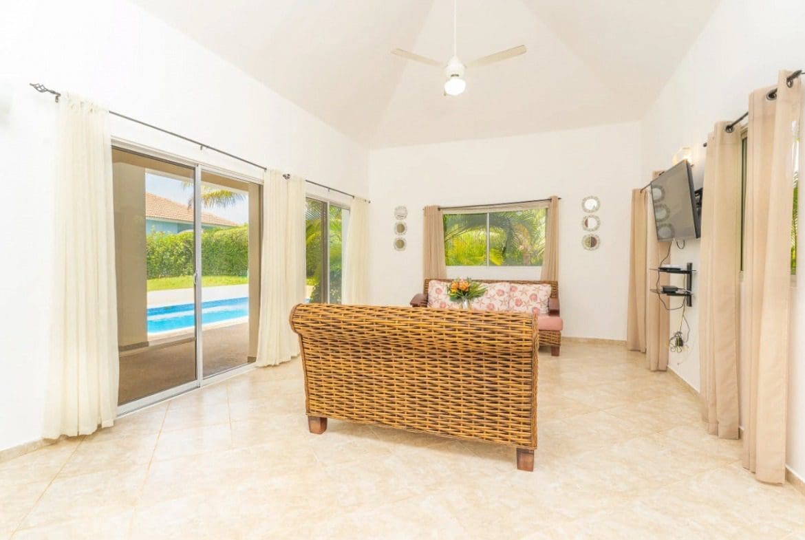 buyDRproperty Spacious living room with wicker furniture and pool view in a beautiful villa Sosua Real Estate