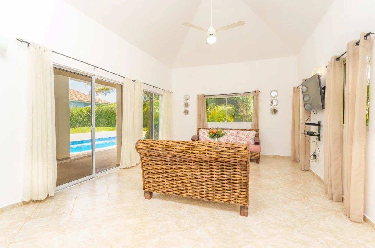 buyDRproperty Spacious living room with wicker furniture and pool view in a beautiful villa Sosua Real Estate
