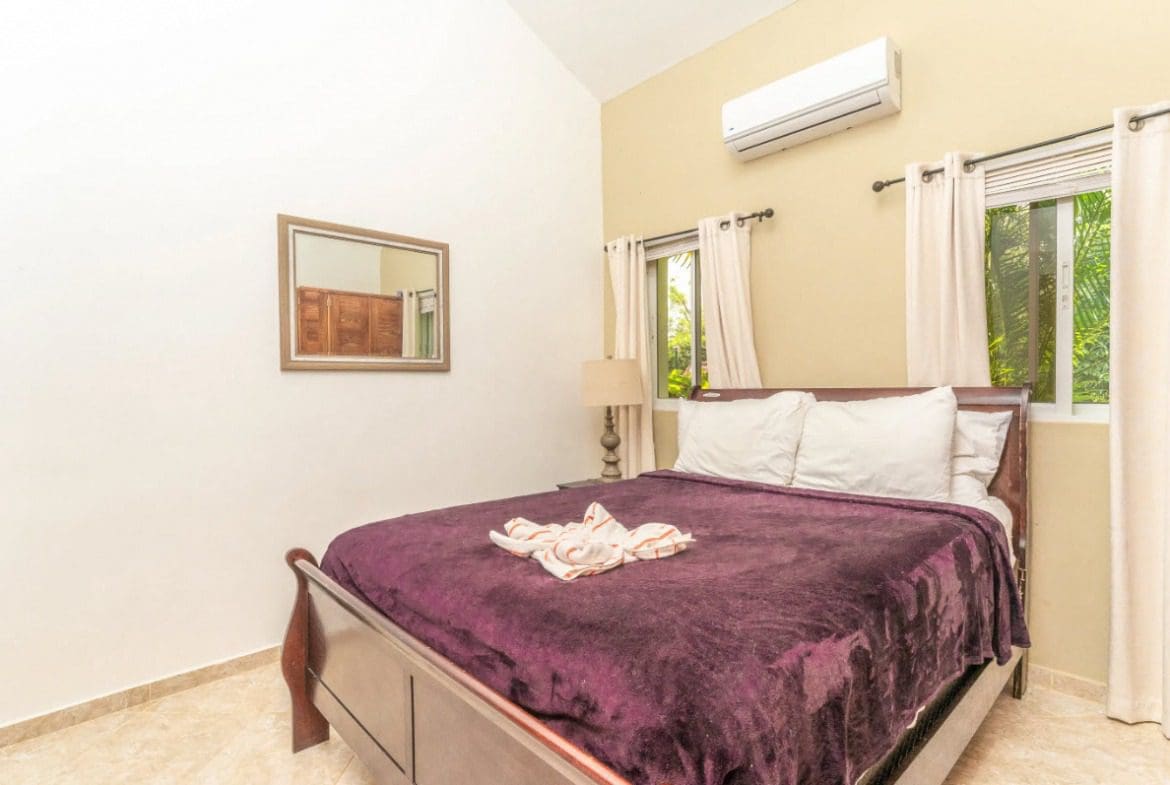 buyDRproperty Bedroom in a villa with a purple blanket and white pillows. Sosua Real Estate