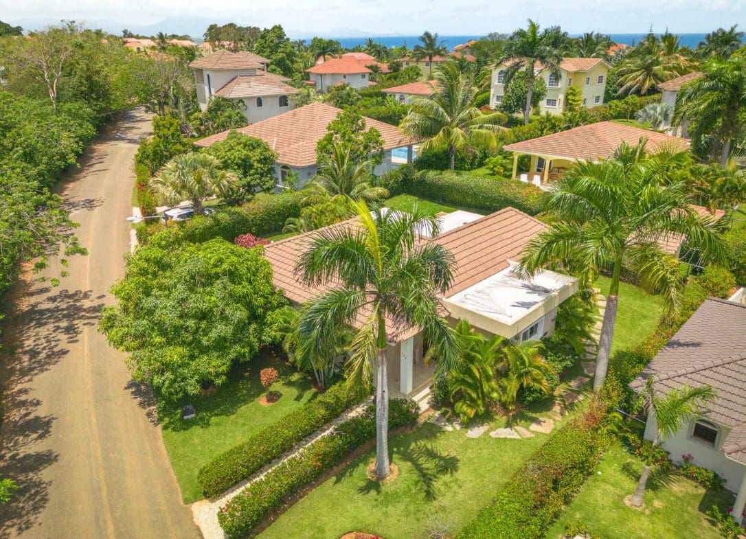 buyDRproperty Aerial view of a beautiful villa in a gated community with palm trees and lush landscaping. Sosua Real Estate
