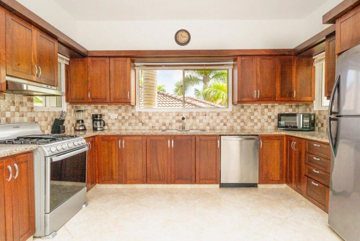 buyDRproperty Stunning kitchen with dark wood cabinets and stainless steel appliances in a villa home. Sosua Real Estate