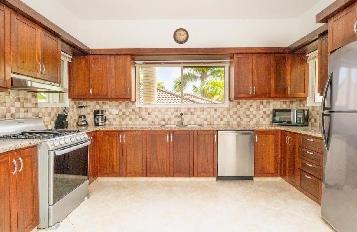 buyDRproperty Stunning kitchen with dark wood cabinets and stainless steel appliances in a villa home. Sosua Real Estate