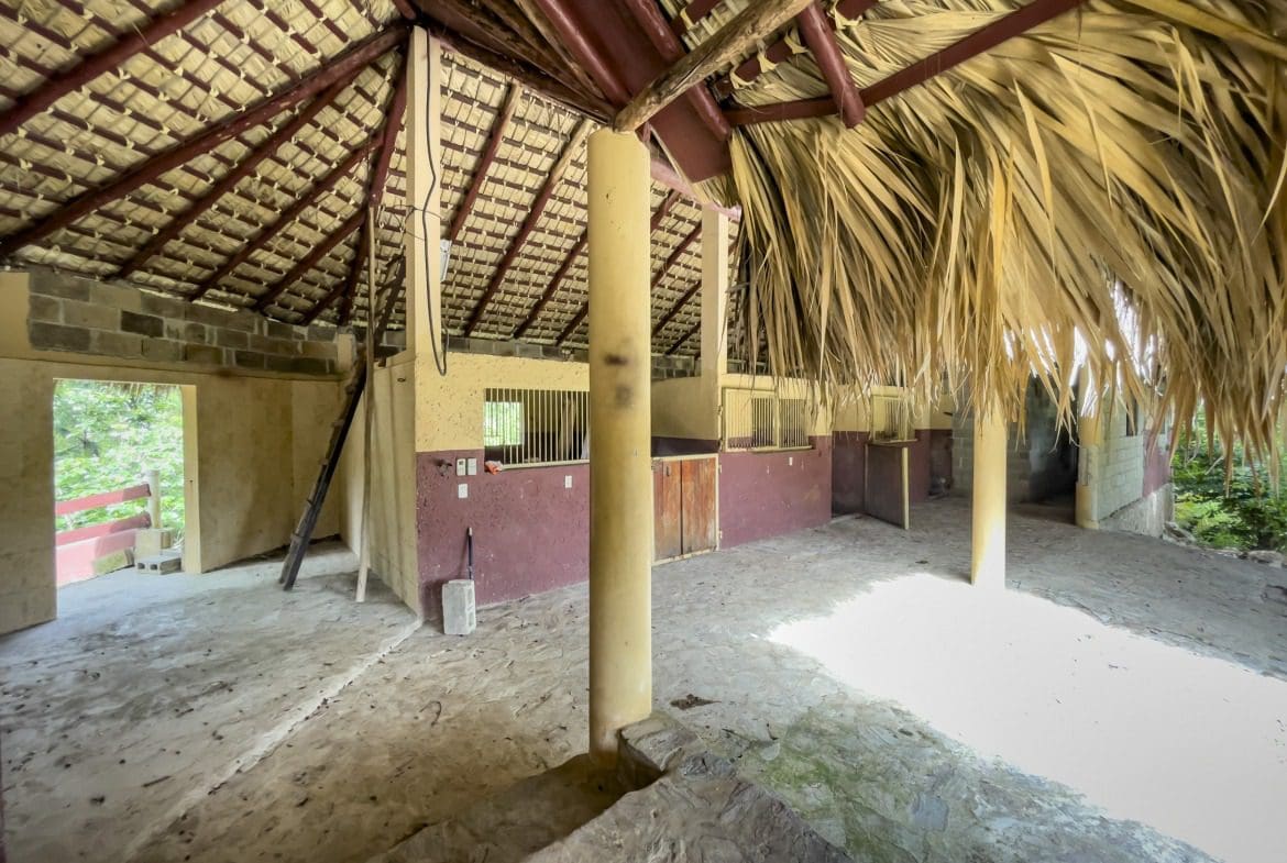 buyDRproperty Exterior of a building lot with a thatched roof and interior stables. Sosua Real Estate