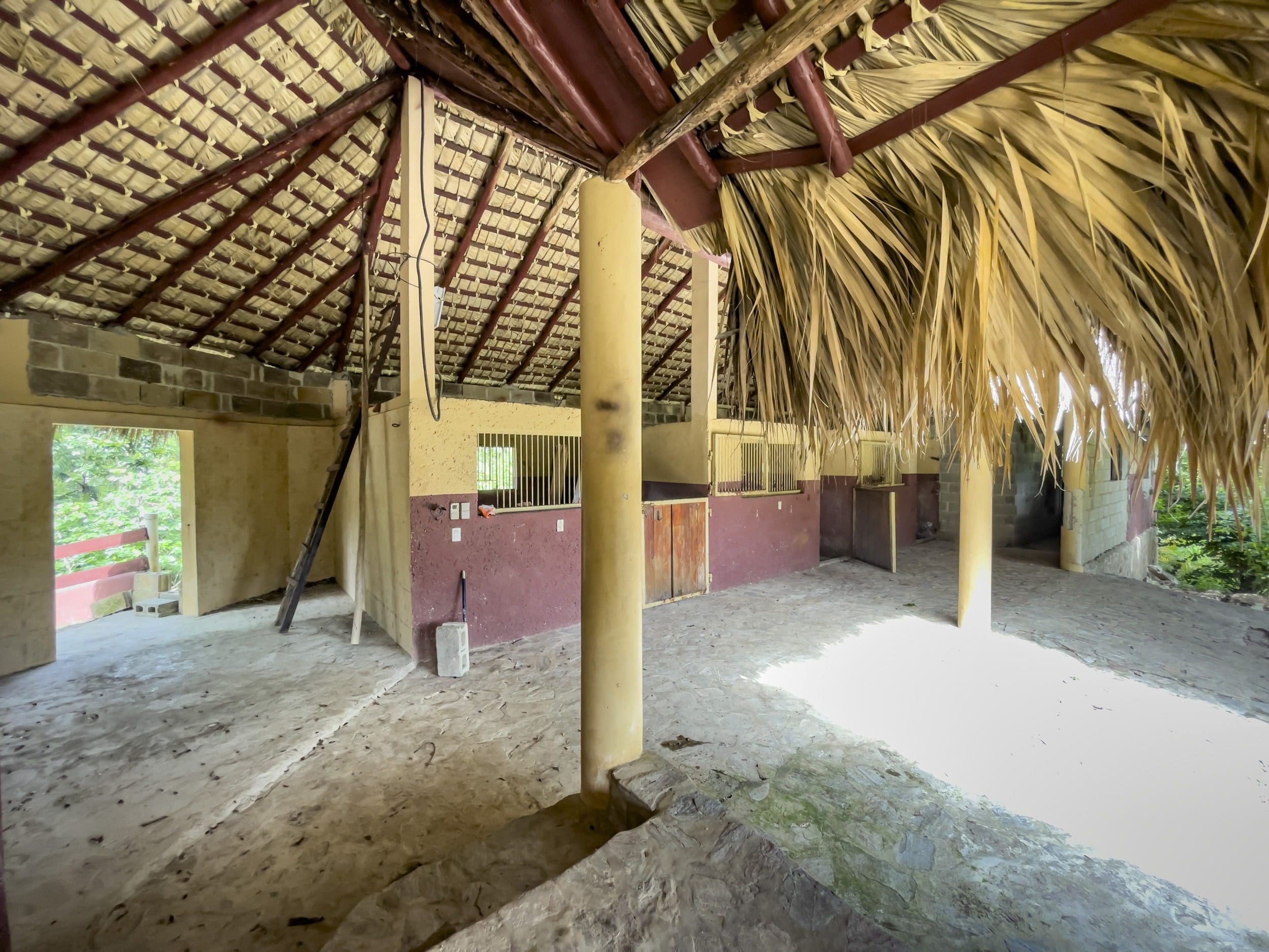 buyDRproperty Exterior of a building lot with a thatched roof and interior stables. Sosua Real Estate