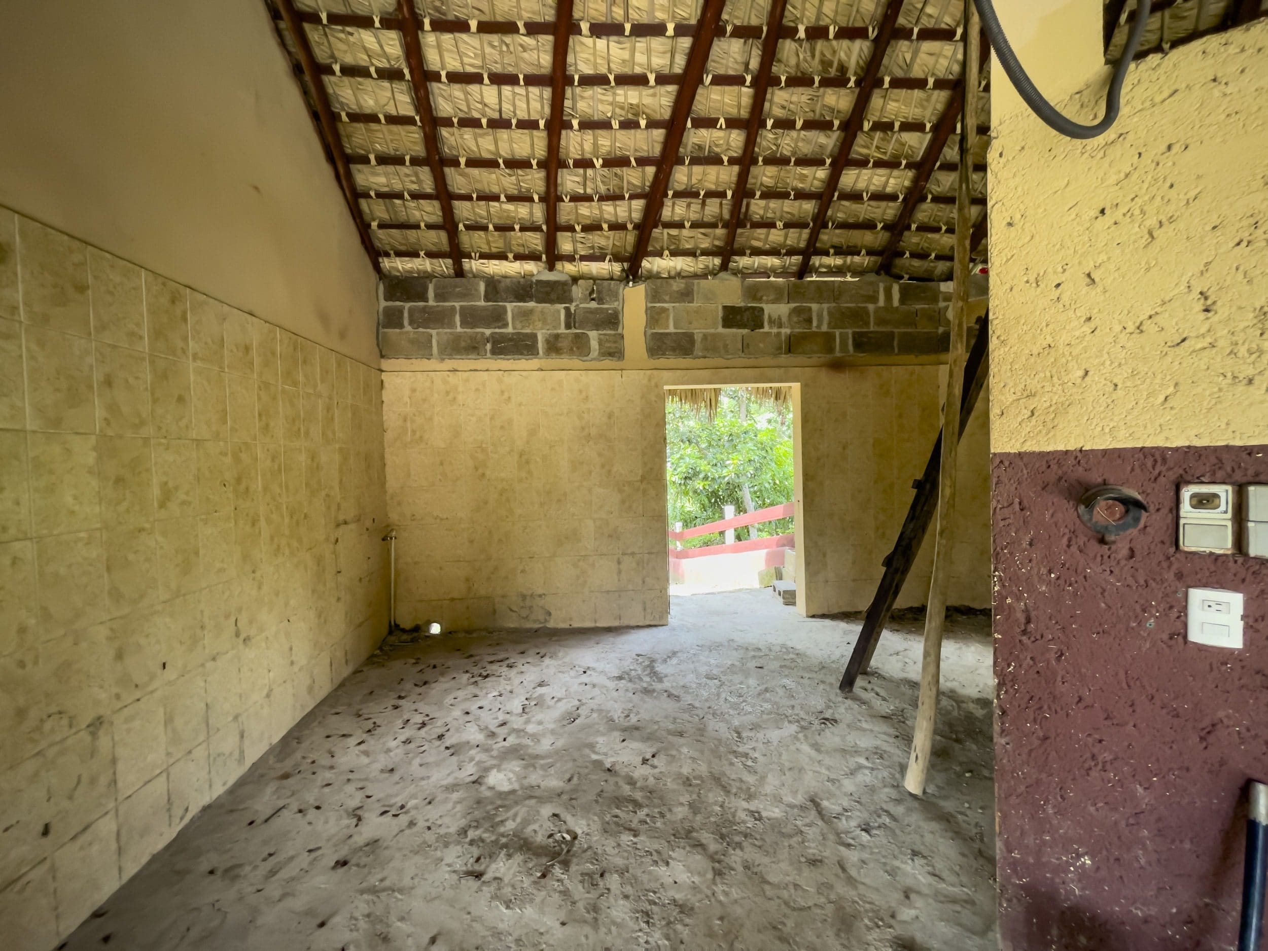 buyDRproperty Interior of a building lot, in disrepair. The room has a tiled wall and open doorway. Sosua Real Estate