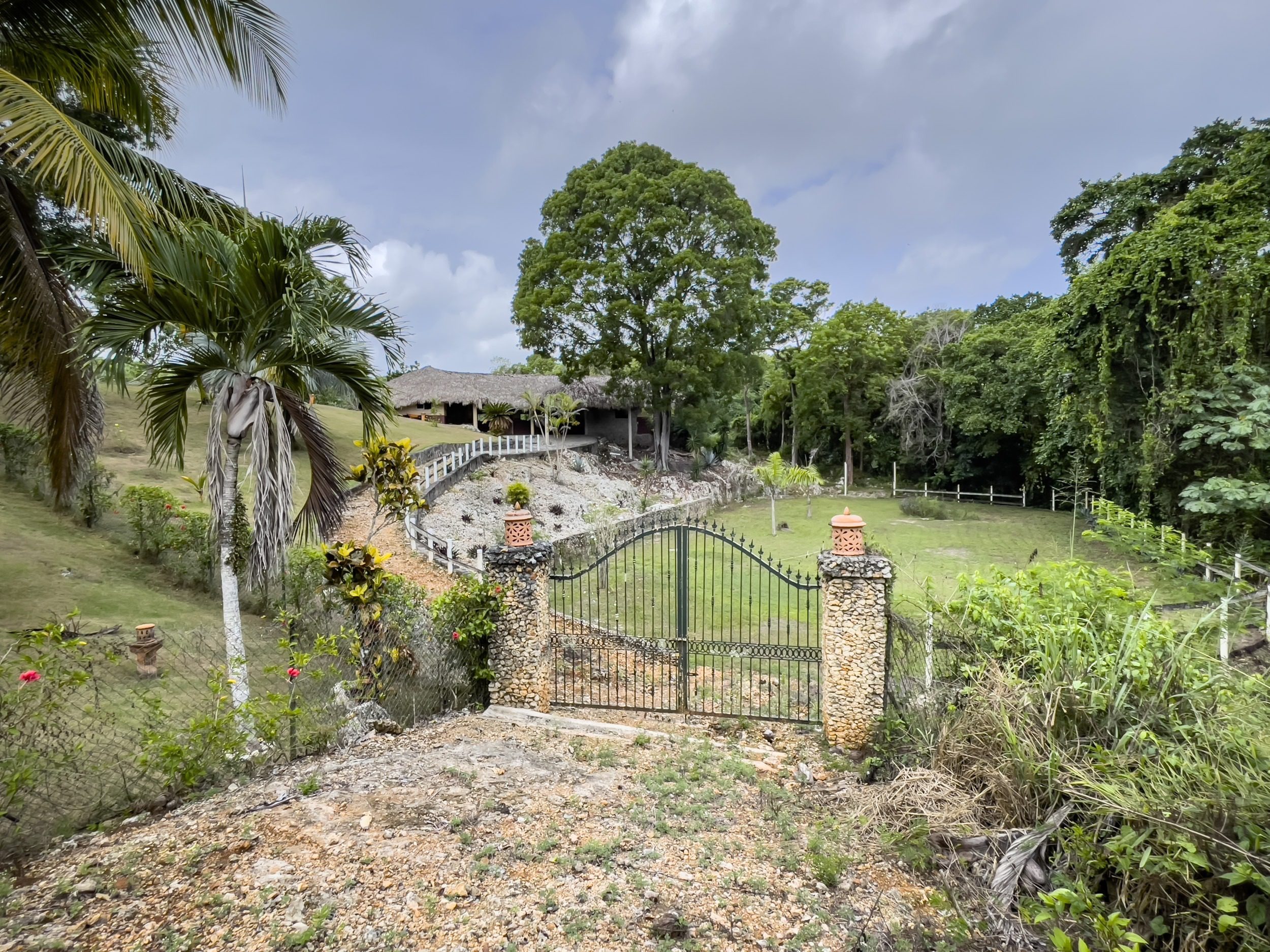 buyDRproperty Entrance to a luxury villa in the Dominican Republic with a stone gate and lush tropical landscaping. Sosua Real Estate