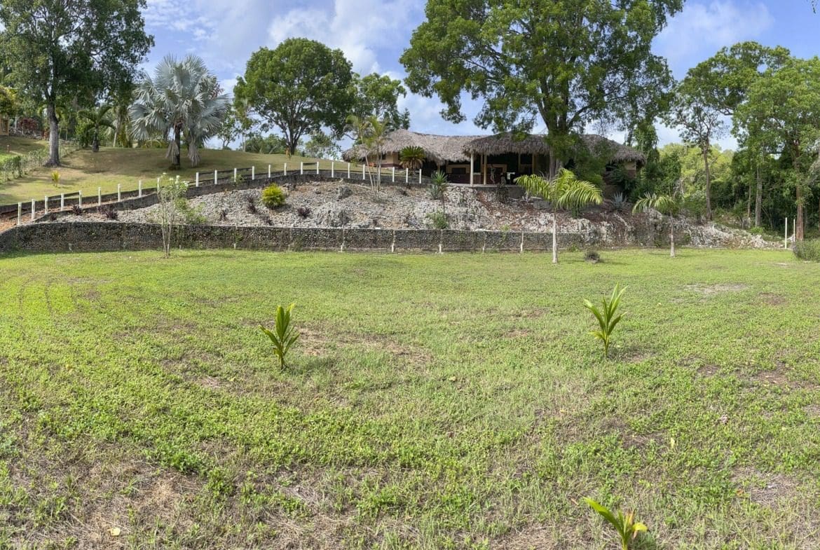 buyDRproperty Building lot with thatched roof and grassy area Sosua Real Estate