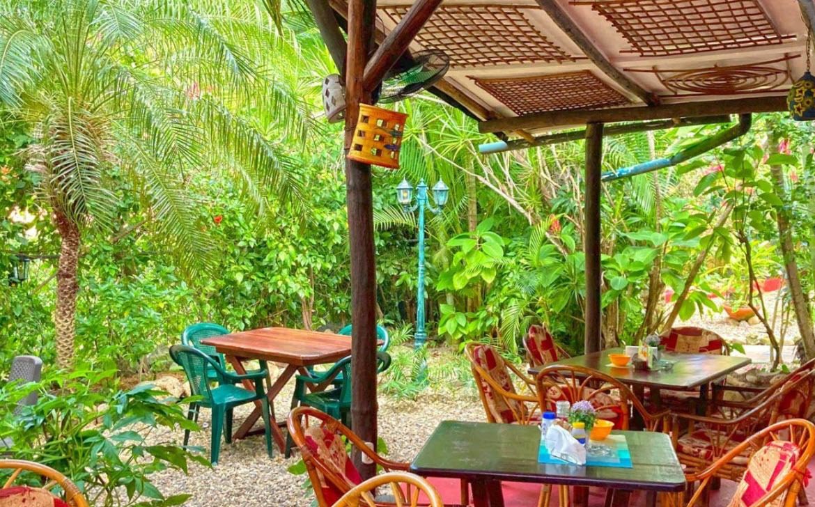 buyDRproperty Outdoor seating area at a Hotel restaurant surrounded by lush greenery. Sosua Real Estate
