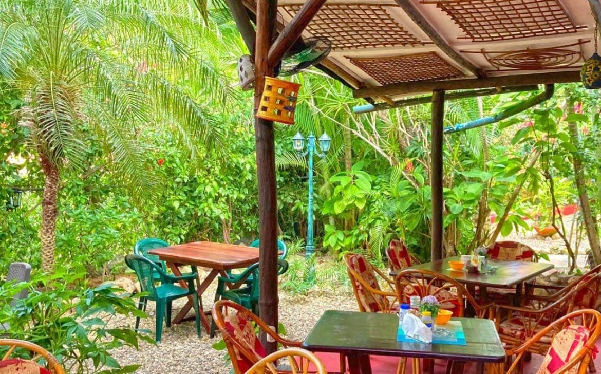 buyDRproperty Outdoor seating area at a Hotel restaurant surrounded by lush greenery. Sosua Real Estate