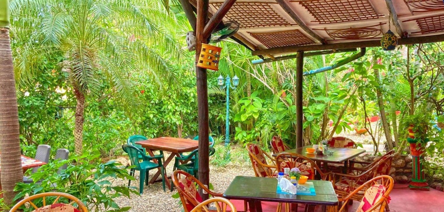 buyDRproperty Outdoor seating area at a Hotel restaurant surrounded by lush greenery. Sosua Real Estate