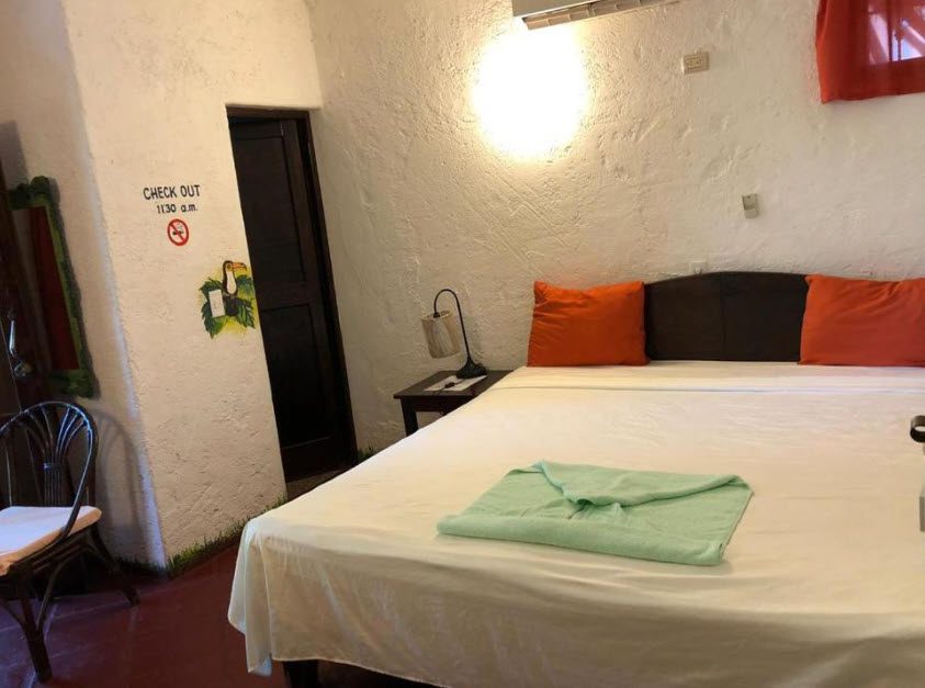 buyDRproperty Hotel room with orange pillows, bed, and a towel. Sosua Real Estate