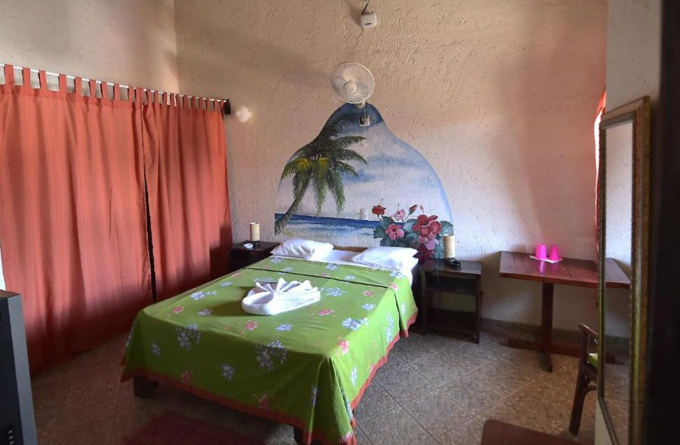 buyDRproperty Hotel room with beach mural and green bedspread. Sosua Real Estate
