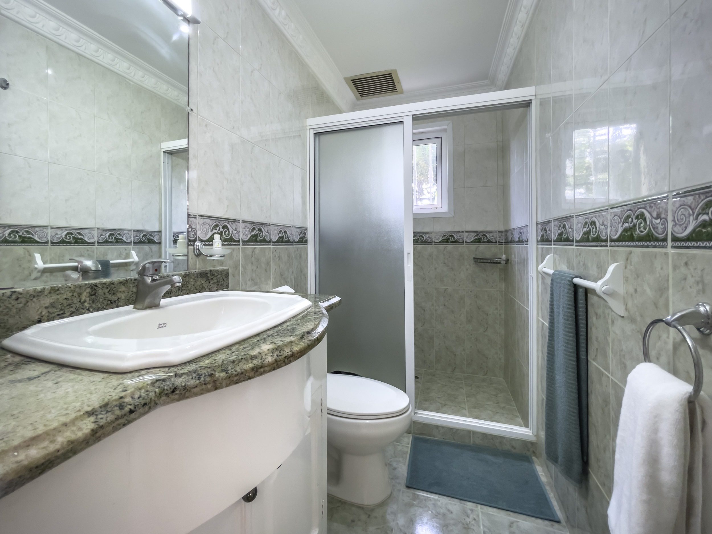 buyDRproperty Bathroom with a white sink and marble countertop. Shower with frosted glass door. Sosua Real Estate
