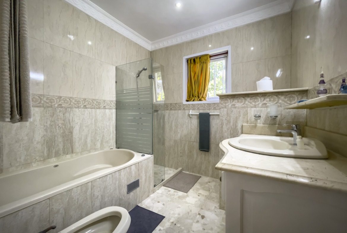 buyDRproperty Bathroom with bathtub, shower, and sink with light-colored tiles. Prime villa bathroom Sosua Real Estate