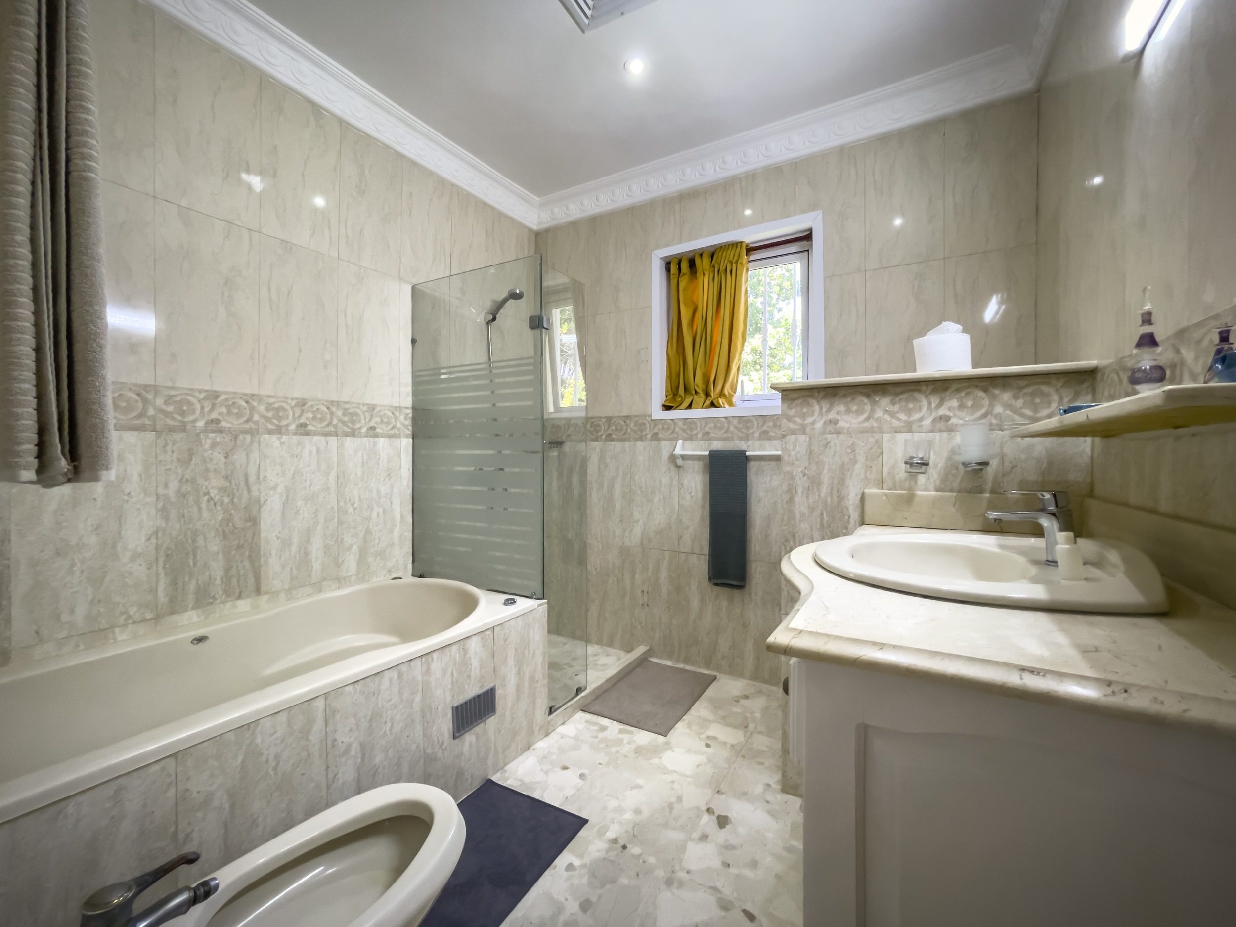 buyDRproperty Bathroom with bathtub, shower, and sink with light-colored tiles. Prime villa bathroom Sosua Real Estate