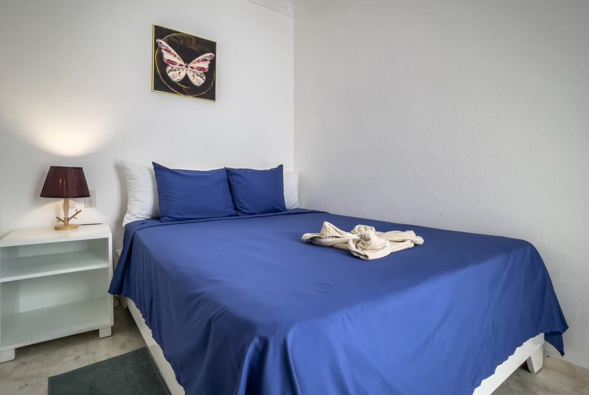 buyDRproperty Bedroom with blue bedding and a prime butterfly artwork. Sosua Real Estate