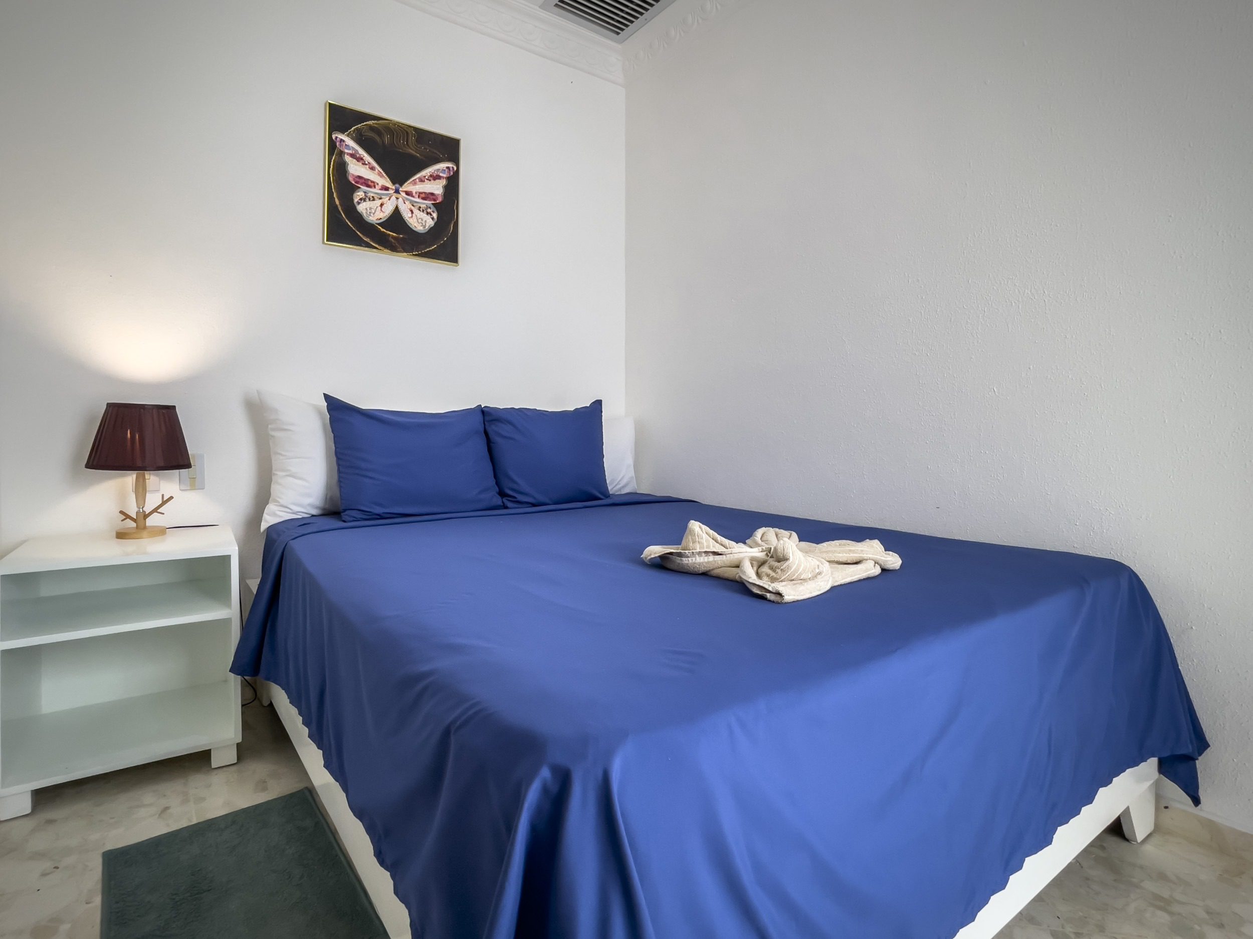 buyDRproperty Bedroom with blue bedding and a prime butterfly artwork. Sosua Real Estate