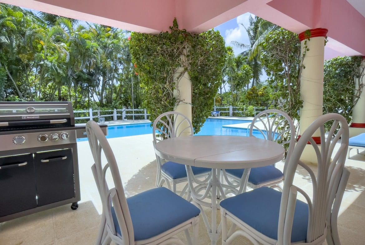 buyDRproperty Outdoor dining area with white furniture and a barbecue grill near a pool. Sosua Real Estate