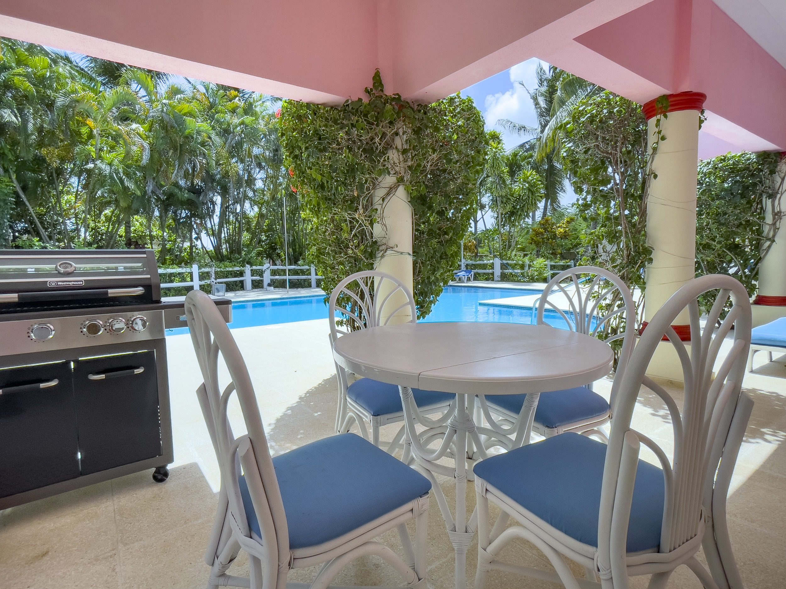 buyDRproperty Outdoor dining area with white furniture and a barbecue grill near a pool. Sosua Real Estate