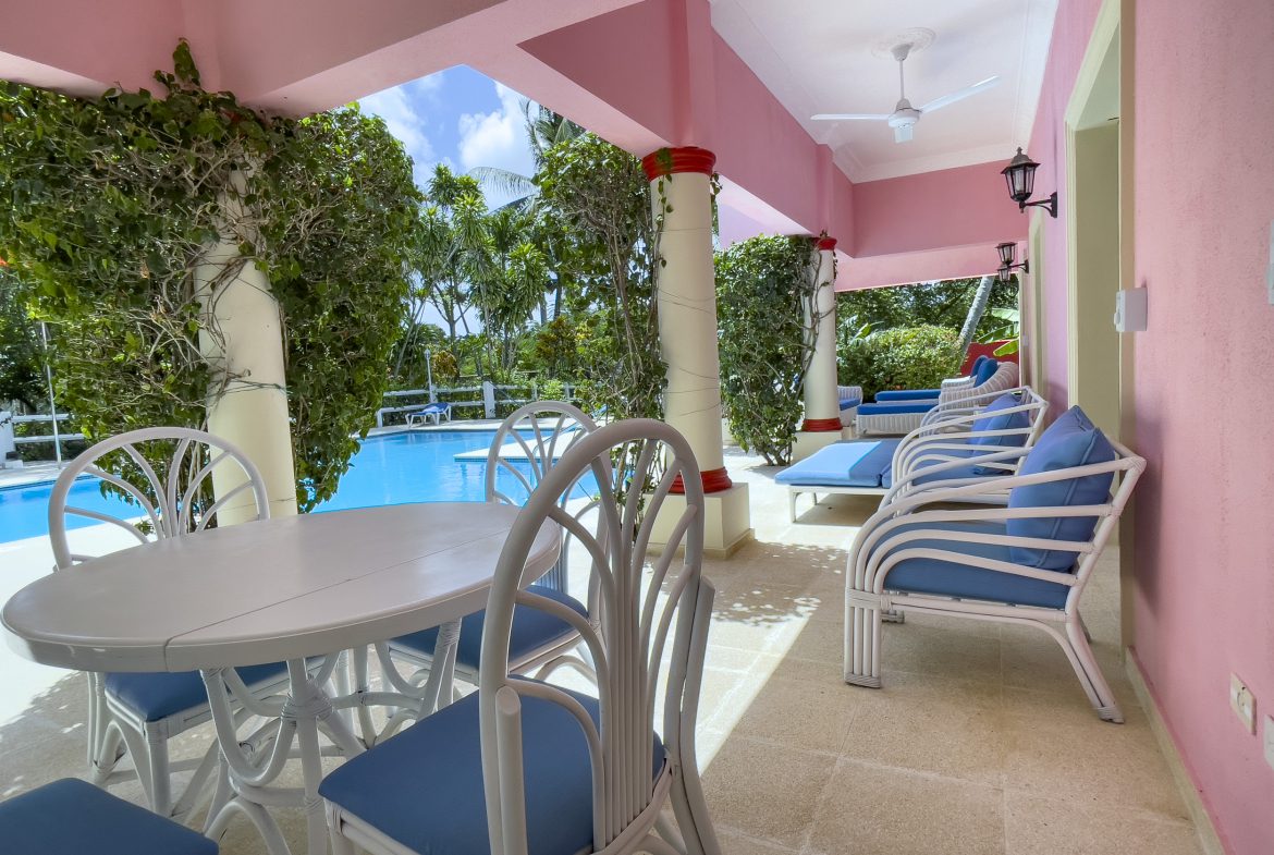 buyDRproperty Prime villa patio with blue cushions, white furniture, and a pool view. Sosua Real Estate
