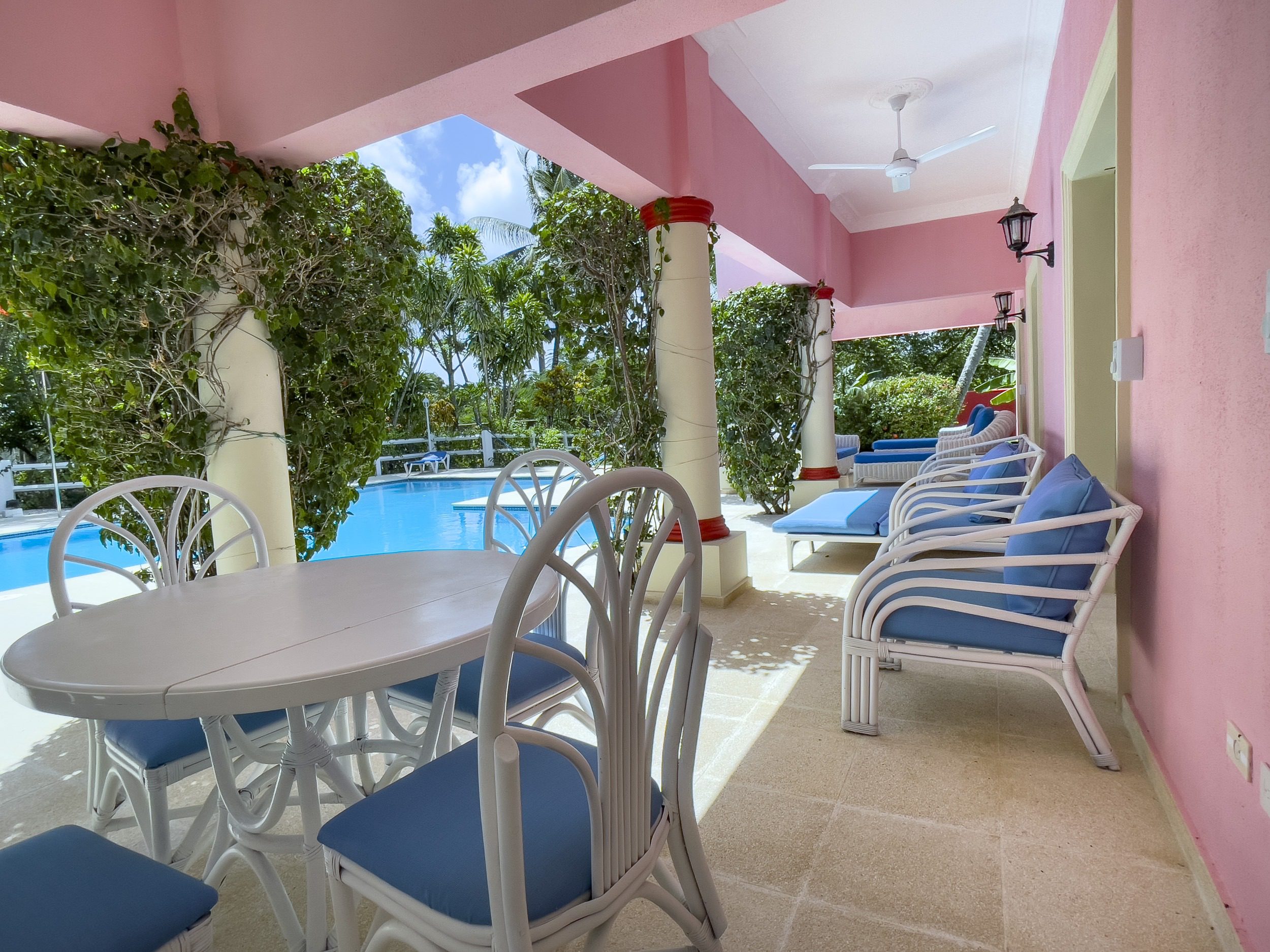 buyDRproperty Prime villa patio with blue cushions, white furniture, and a pool view. Sosua Real Estate