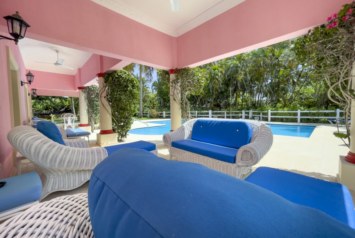 buyDRproperty Covered patio with white wicker furniture, blue cushions, and a pool. Prime villa. Sosua Real Estate