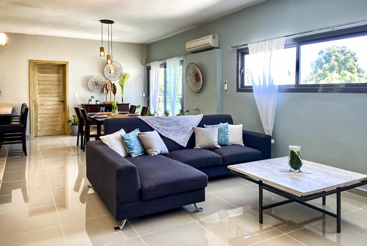 buyDRproperty Modern living room with dark blue sectional sofa and wooden coffee table. Sosua Real Estate