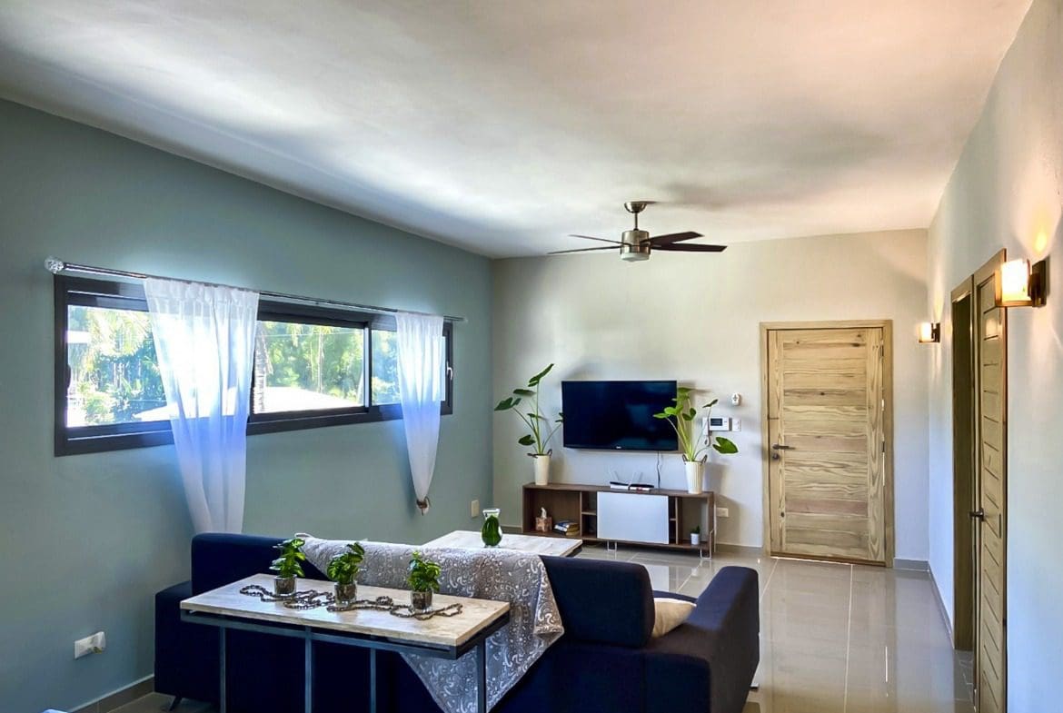 buyDRproperty Modern living room with blue sofa, TV, and windows. For sale! 2 Bedroom Penthouse in ProCab Sosua Real Estate