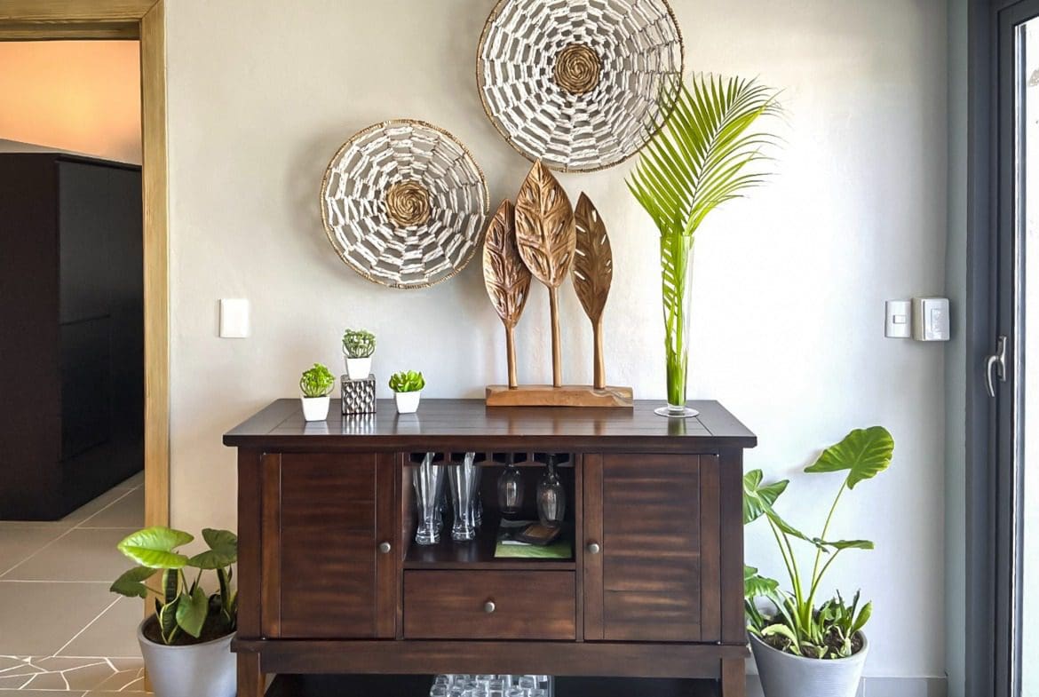buyDRproperty Stylish dark wood cabinet with decorative wall hangings. Plants add a touch of greenery. Sosua Real Estate