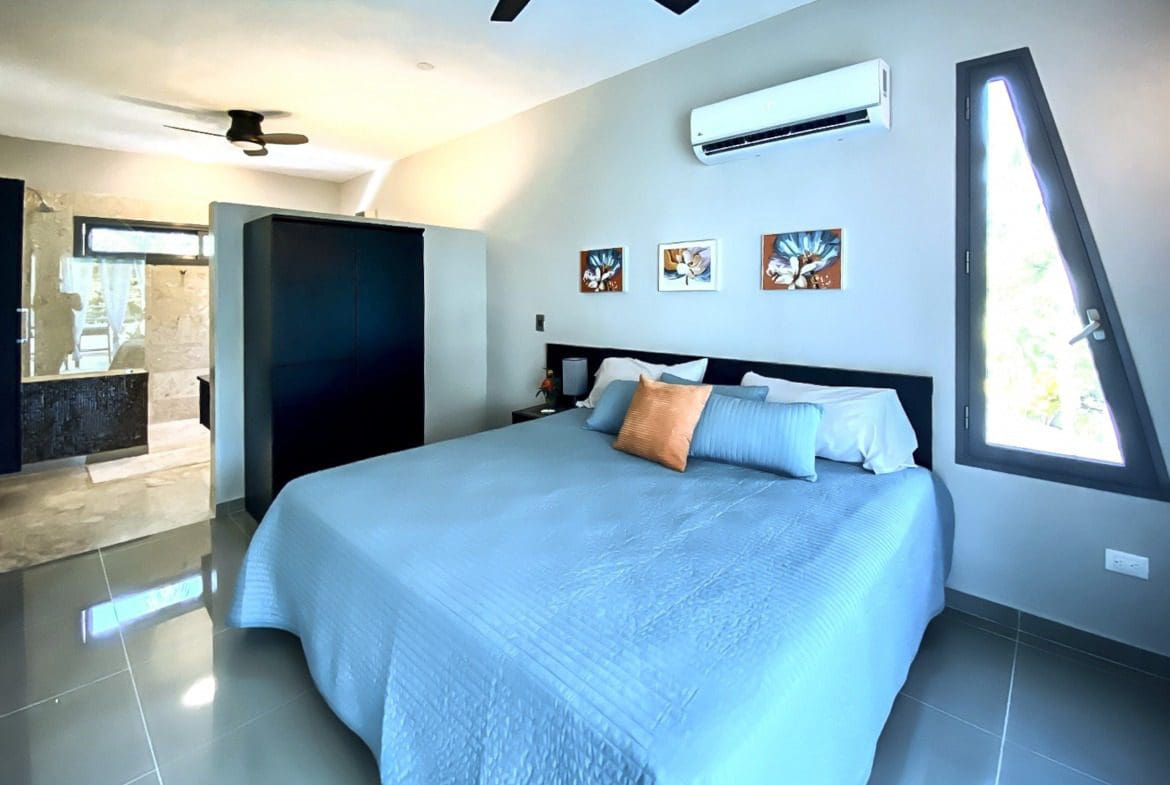 buyDRproperty Modern bedroom in a ProCab penthouse for sale, featuring blue bedding and a unique window. Sosua Real Estate