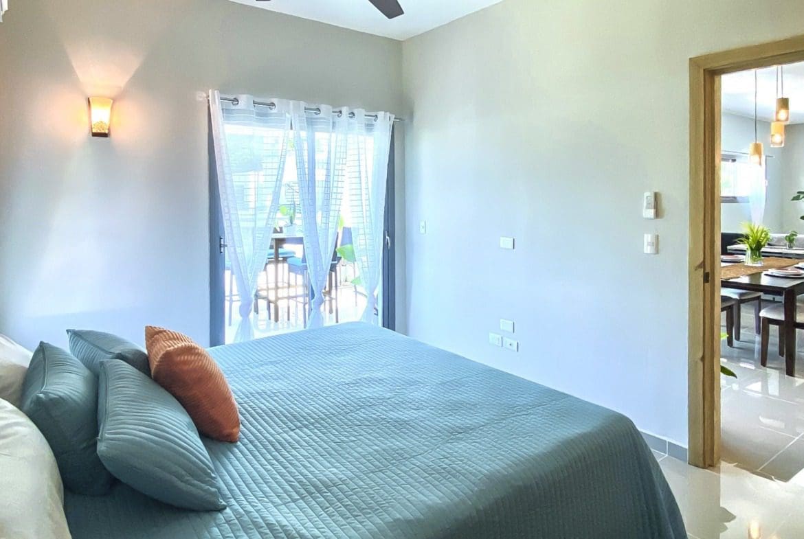 buyDRproperty Bedroom of a 2-bedroom penthouse for sale in ProCab with teal bedding and orange pillow Sosua Real Estate