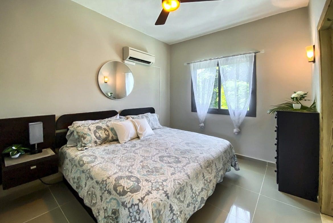 buyDRproperty Bedroom with bed, mirror, and window in a ProCab penthouse. Sosua Real Estate