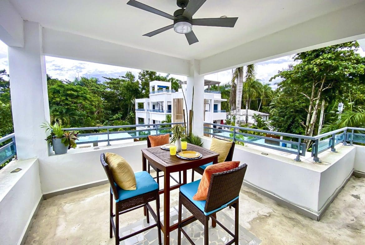 buyDRproperty Balcony dining set with view of lush greenery and a building in ProCab. Sosua Real Estate