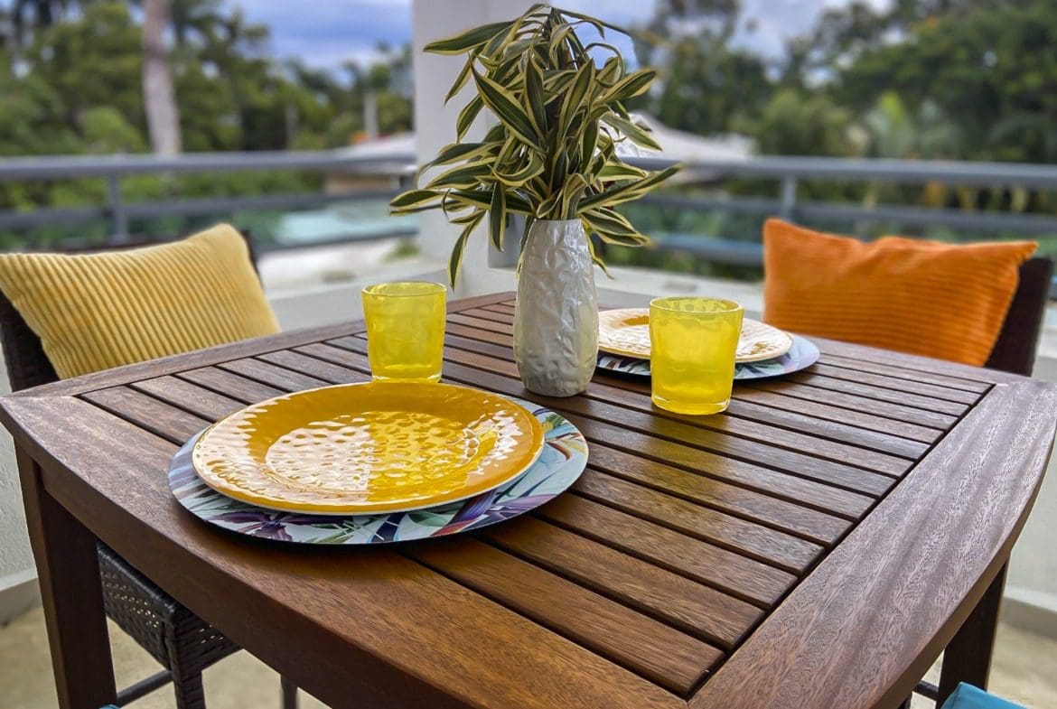 buyDRproperty Outdoor dining table set with plates, glasses, and a vase of plants, creating a relaxing atmosphere. Sosua Real Estate