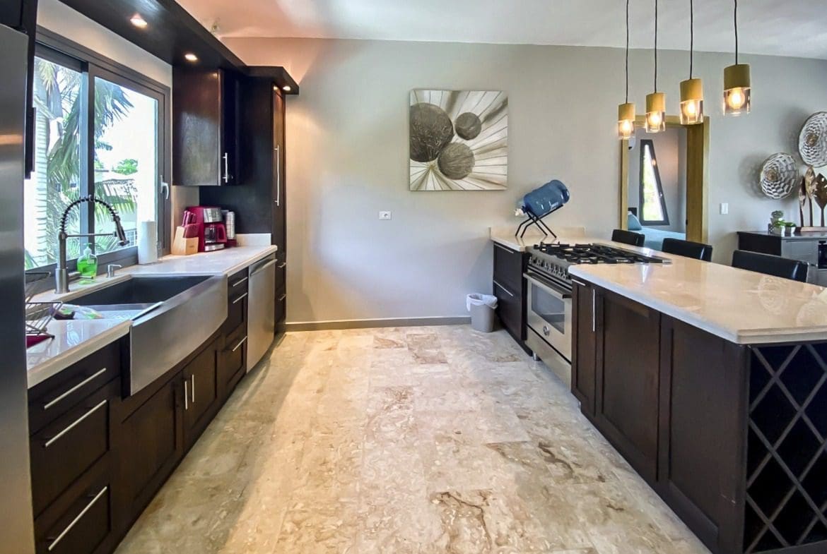 buyDRproperty Modern kitchen with dark cabinets, stainless steel appliances, and a large island. Sosua Real Estate