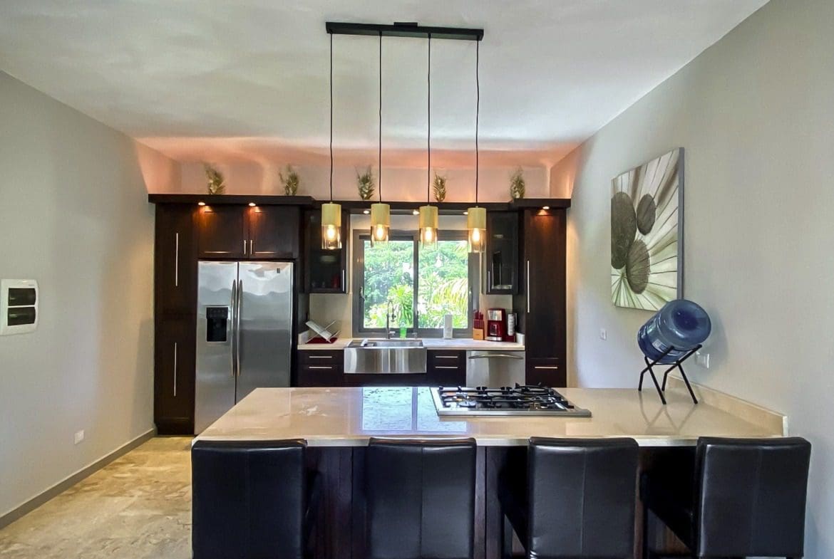 buyDRproperty Modern kitchen with dark cabinets, stainless steel appliances, and a breakfast bar with seating. Sosua Real Estate
