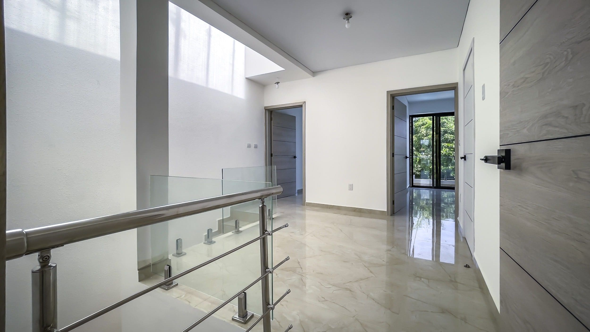 buyDRproperty Modern hallway with glass railing, marble floors, and natural light. Sosua Real Estate