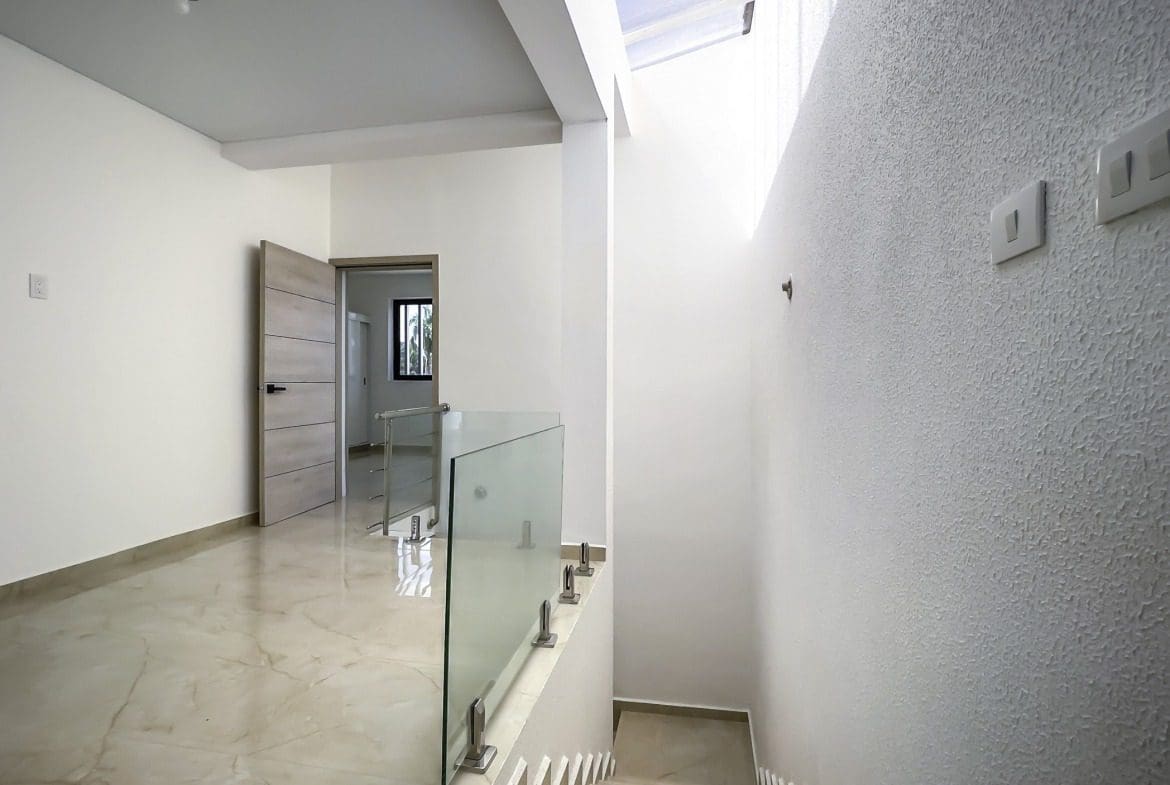 buyDRproperty Modern condo hallway with staircase and glass railing Sosua Real Estate
