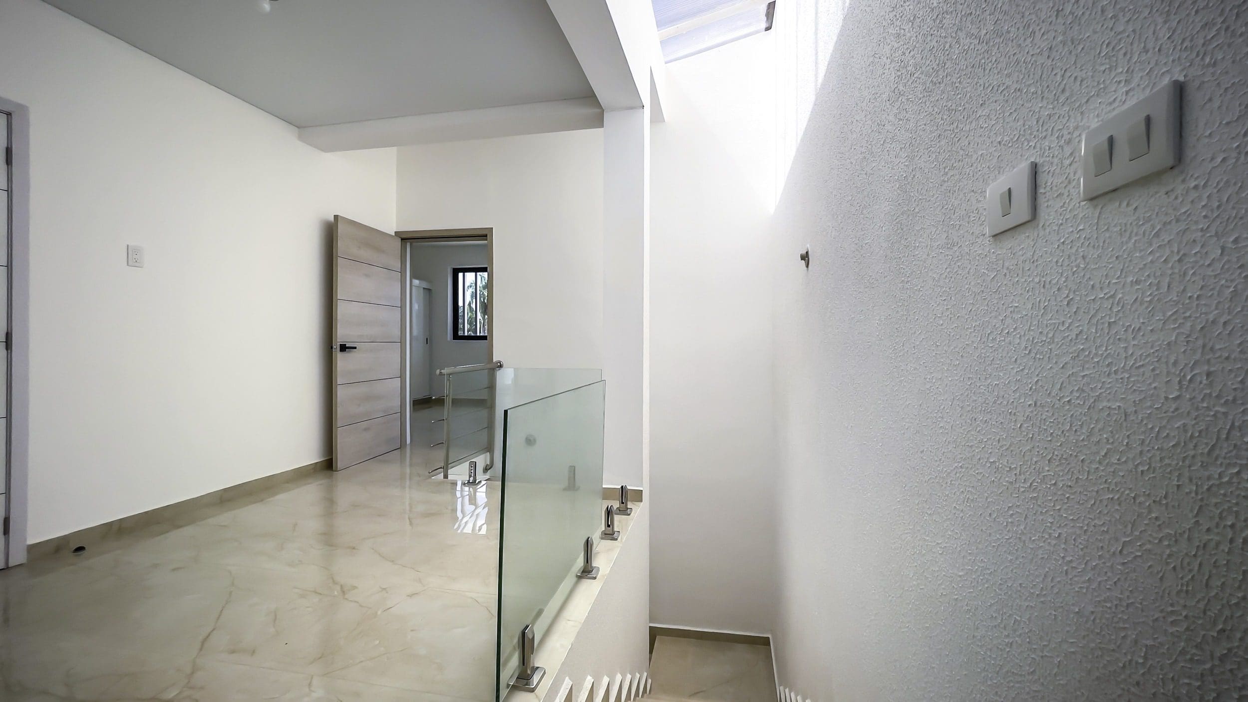 buyDRproperty Modern condo hallway with staircase and glass railing Sosua Real Estate