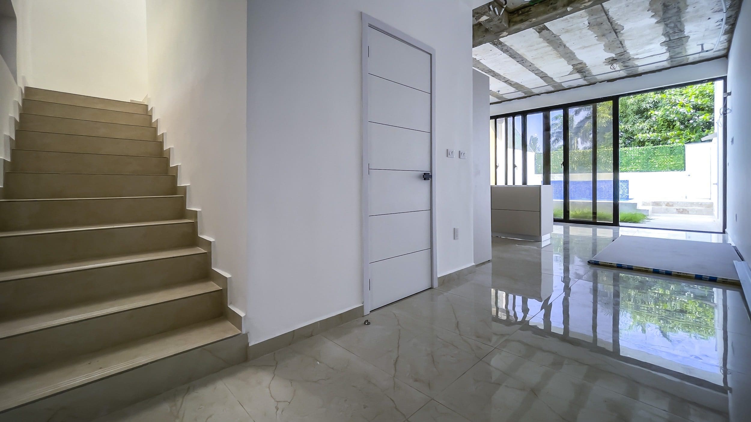 buyDRproperty Modern condo interior with stairs, door, and hallway leading to outdoor view. Sosua Real Estate