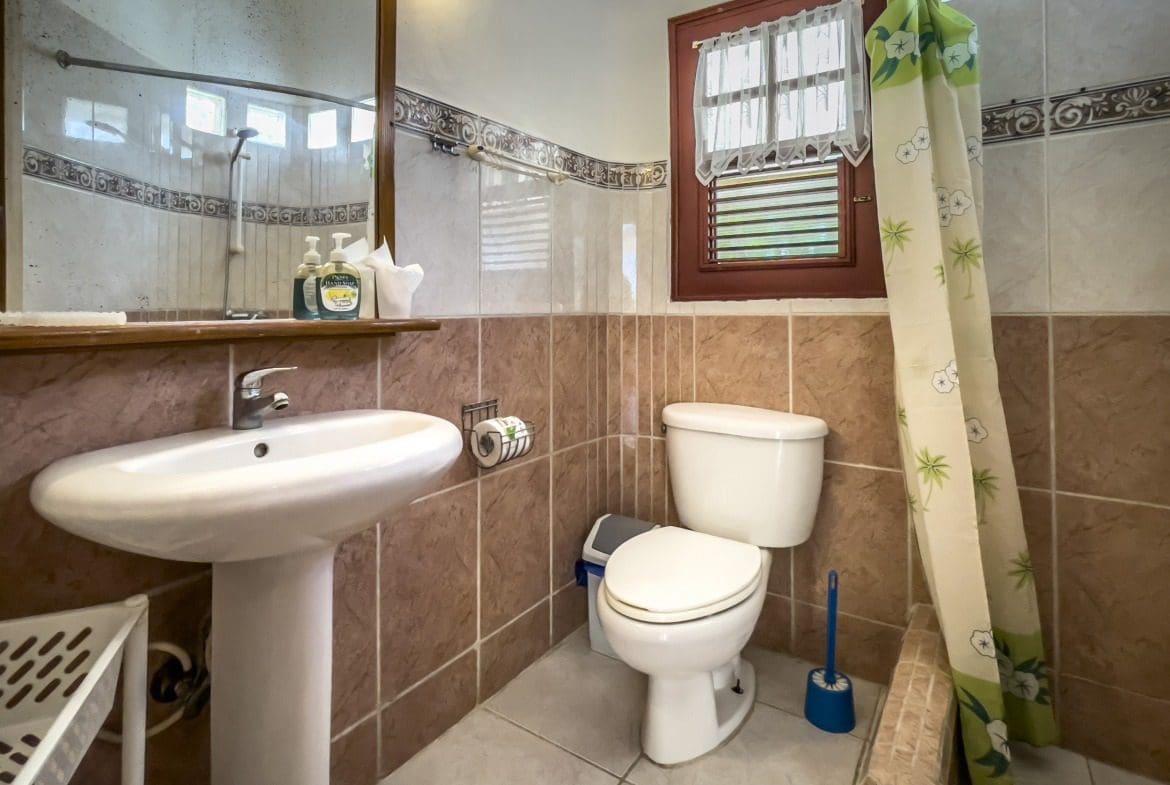 buyDRproperty Bathroom in a B&B with a white sink, toilet, and shower curtain. Sosua Real Estate