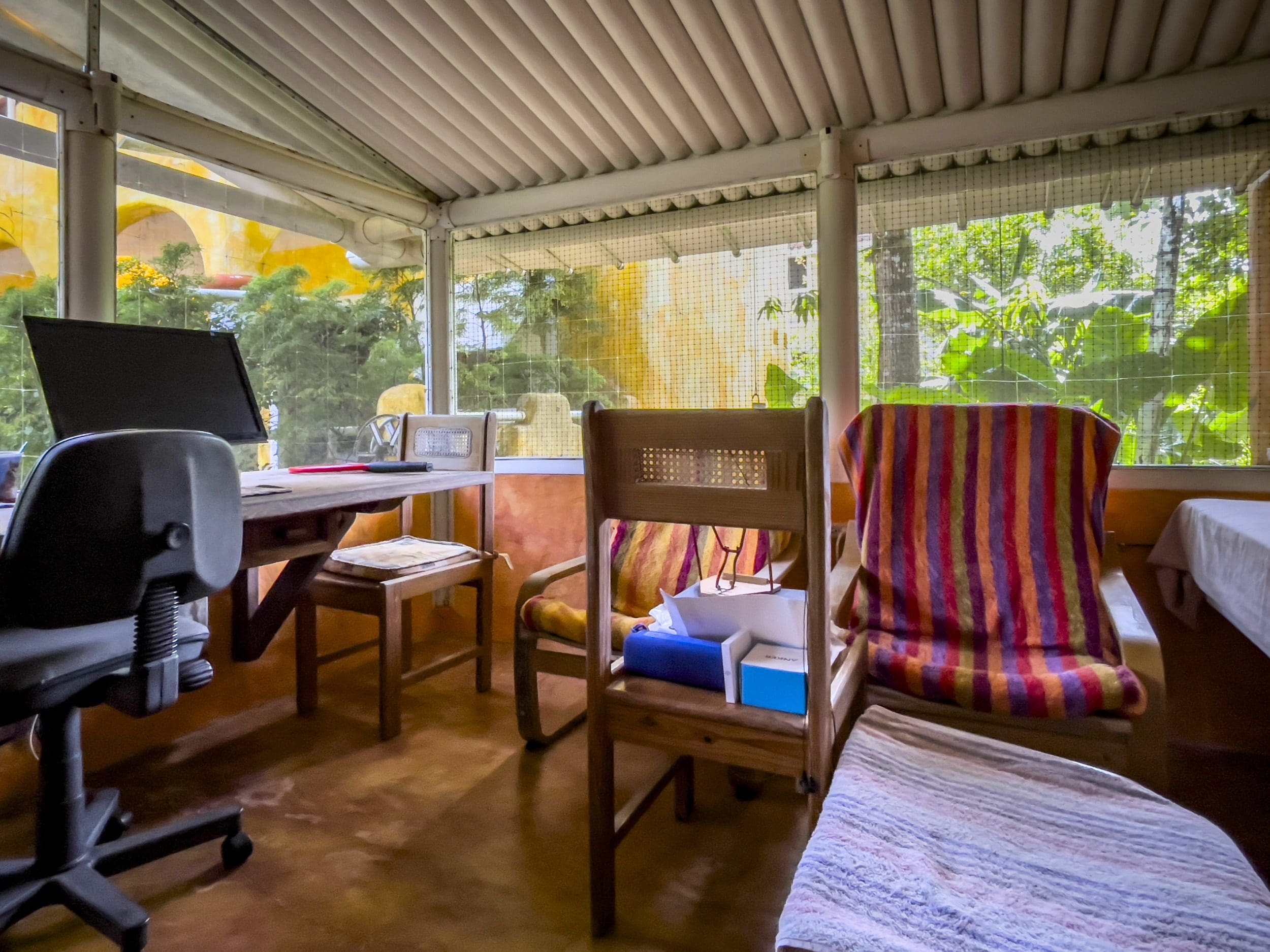buyDRproperty Cozy B&B interior with desk and chairs, overlooking a lush outdoor view. Sosua Real Estate