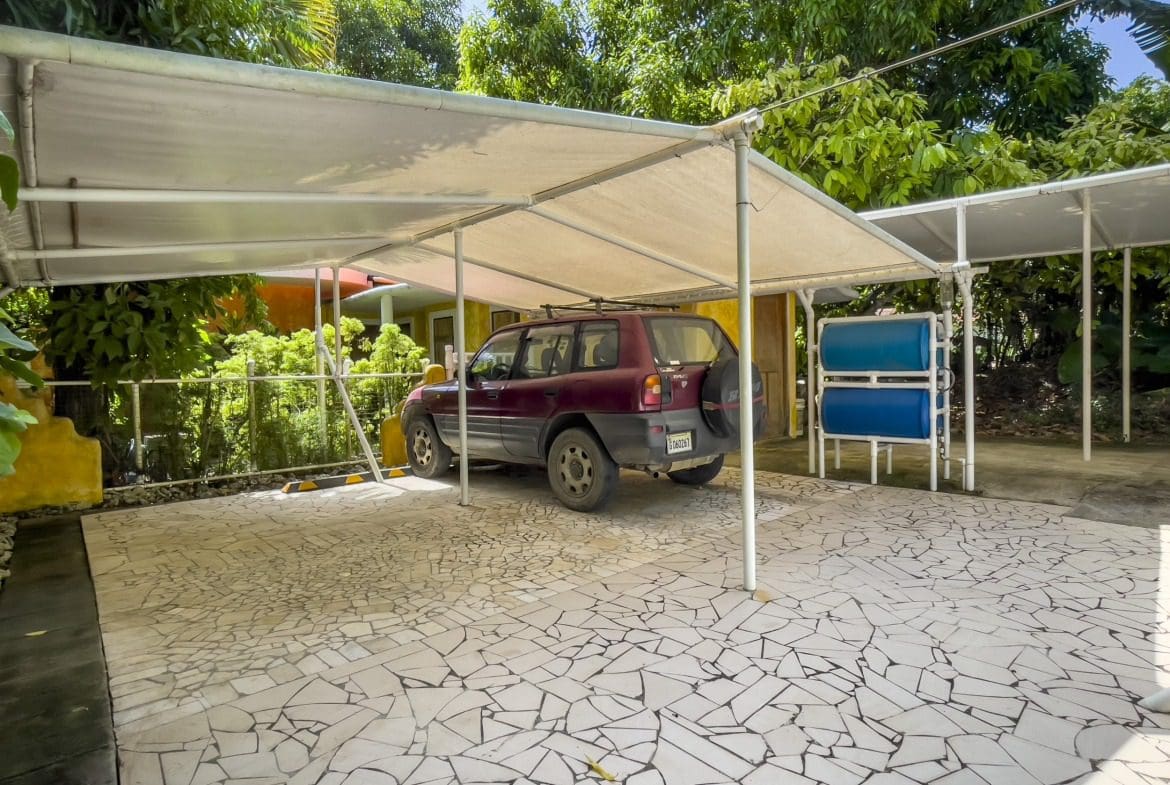 buyDRproperty Red SUV parked under a carport at a B&B Sosua Real Estate