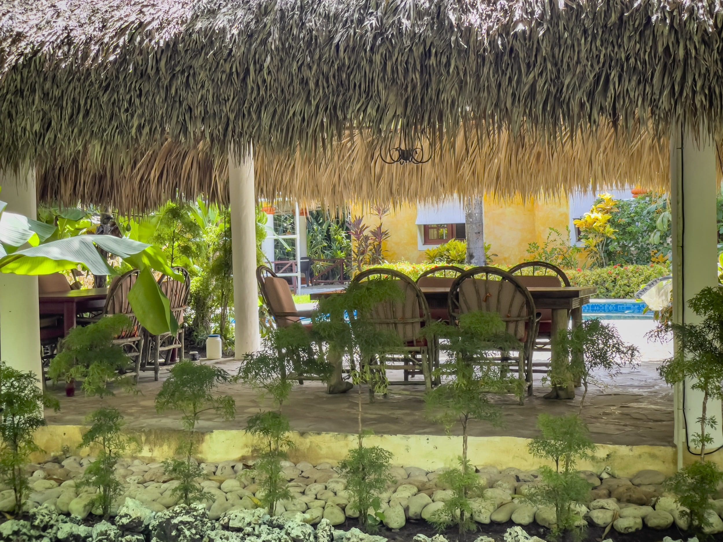 buyDRproperty Charming B&B outdoor dining area with thatched roof and lush greenery. Sosua Real Estate
