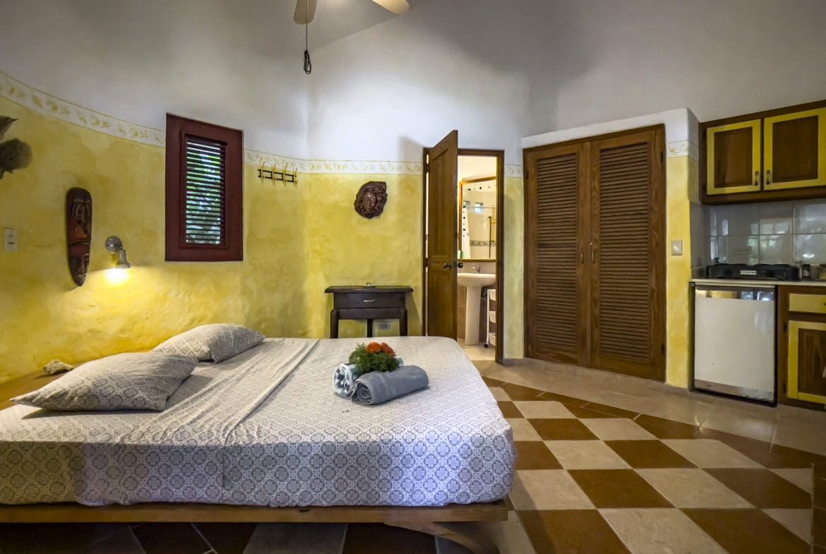 buyDRproperty Bedroom in a charming B&B with a bed, window, and kitchenette. Sosua Real Estate