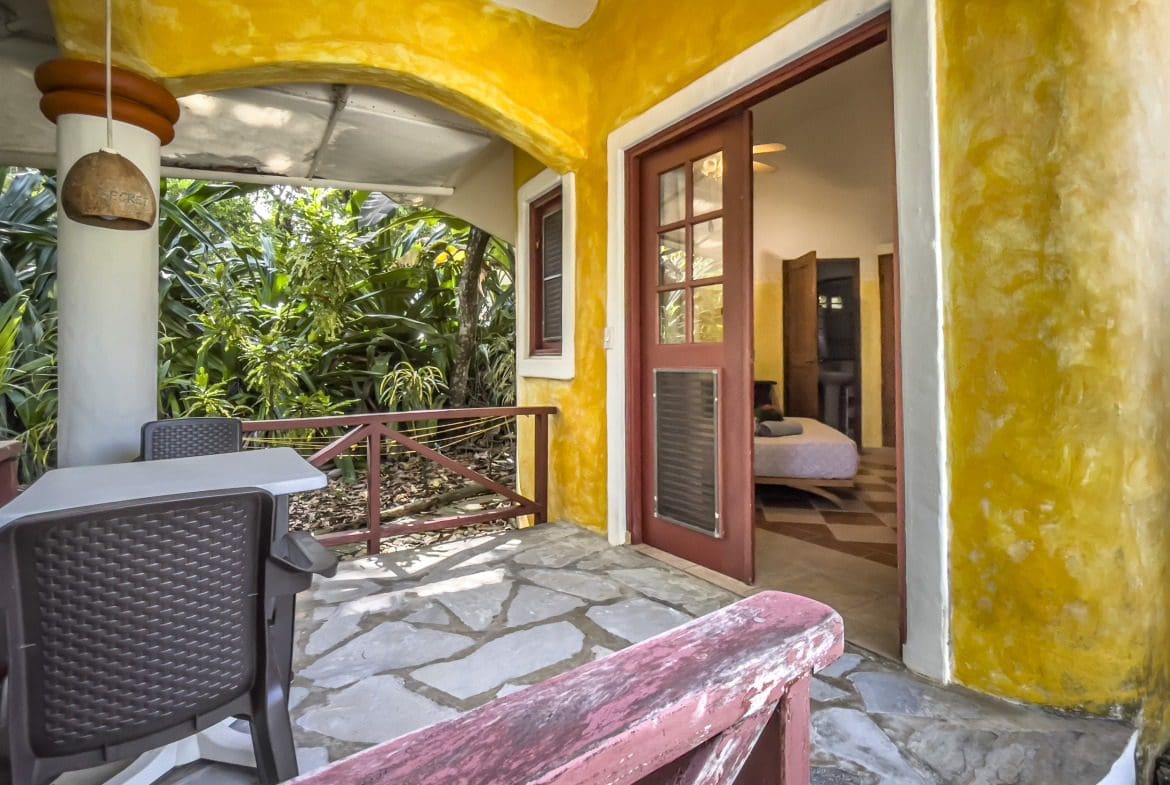 buyDRproperty Charming B&B porch with door open to bedroom, looking out to lush greenery. Sosua Real Estate